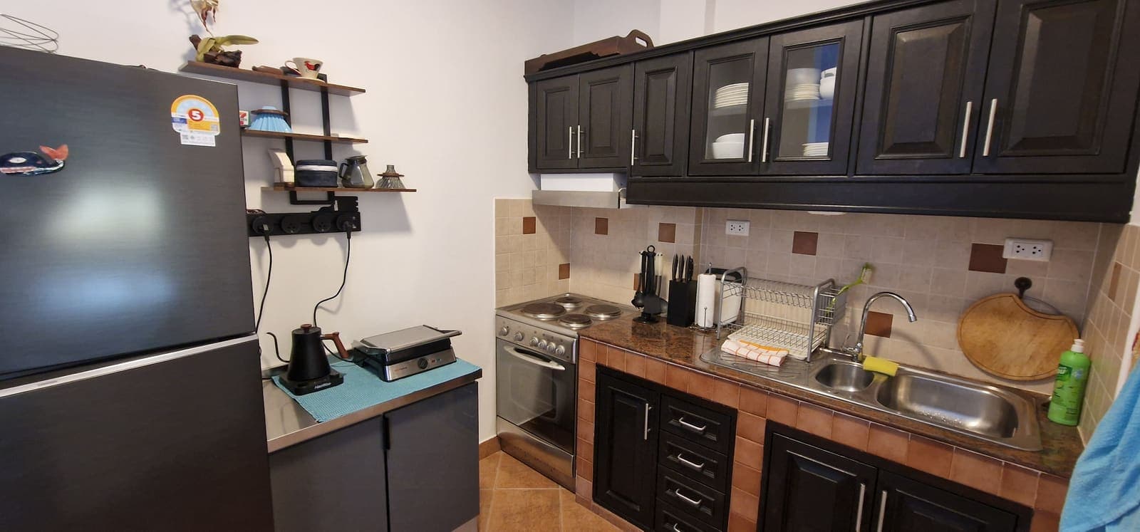 Western-style kitchen with dark cabinets, stove and refrigerator
