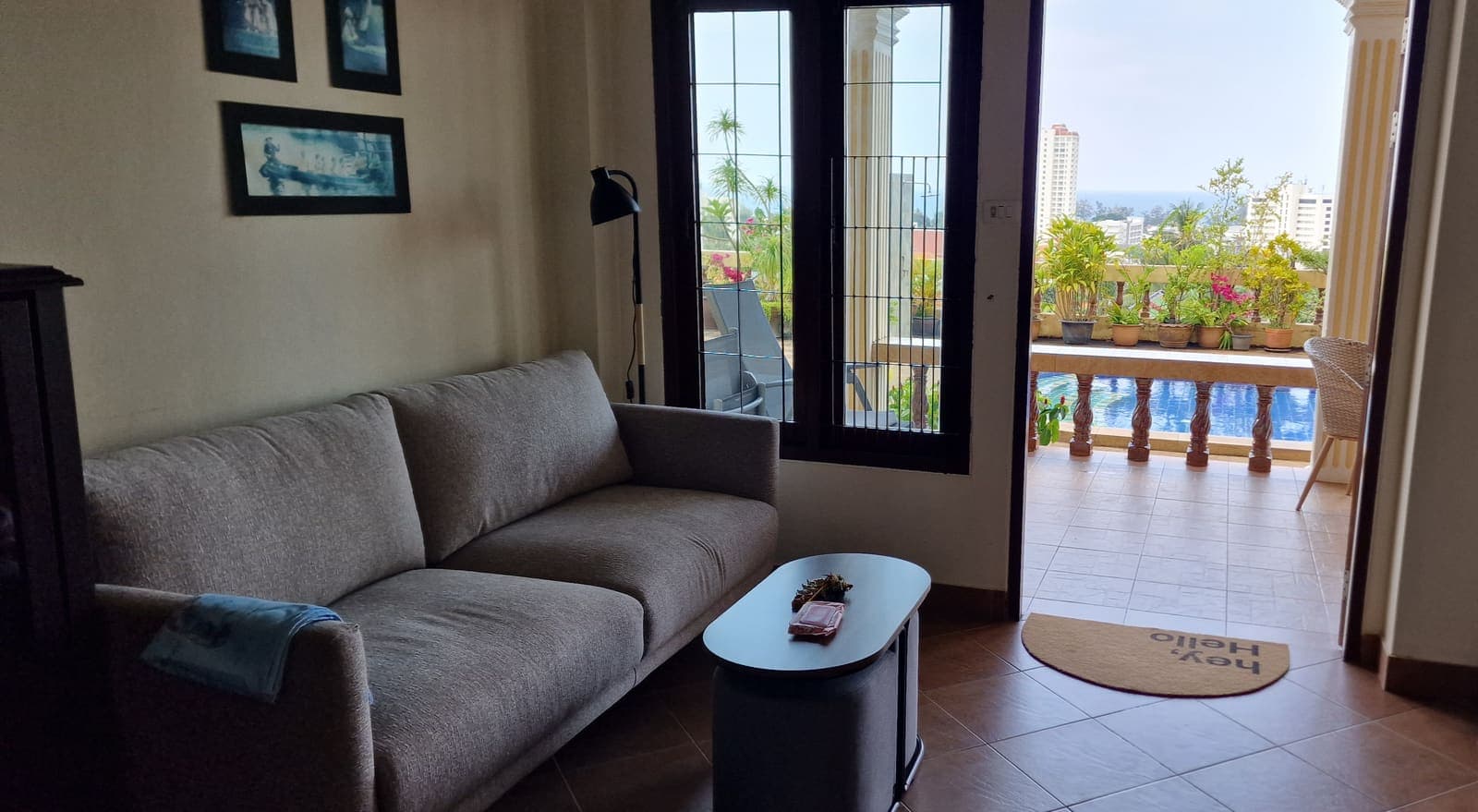 Bright living room with an open balcony door showing the pool and view