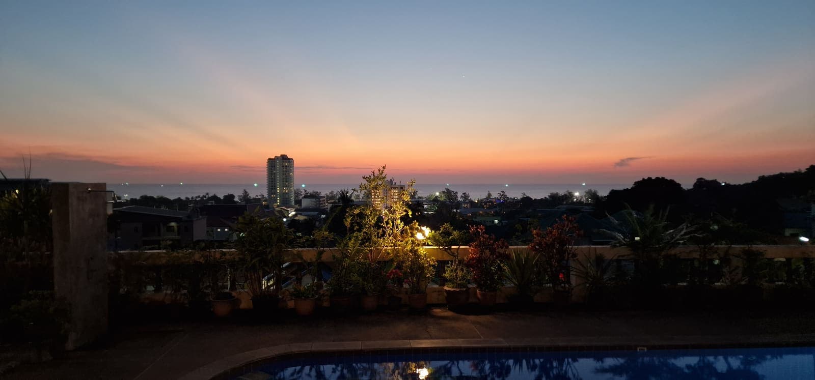 Dusk view of the pool with city lights coming on in the distance
