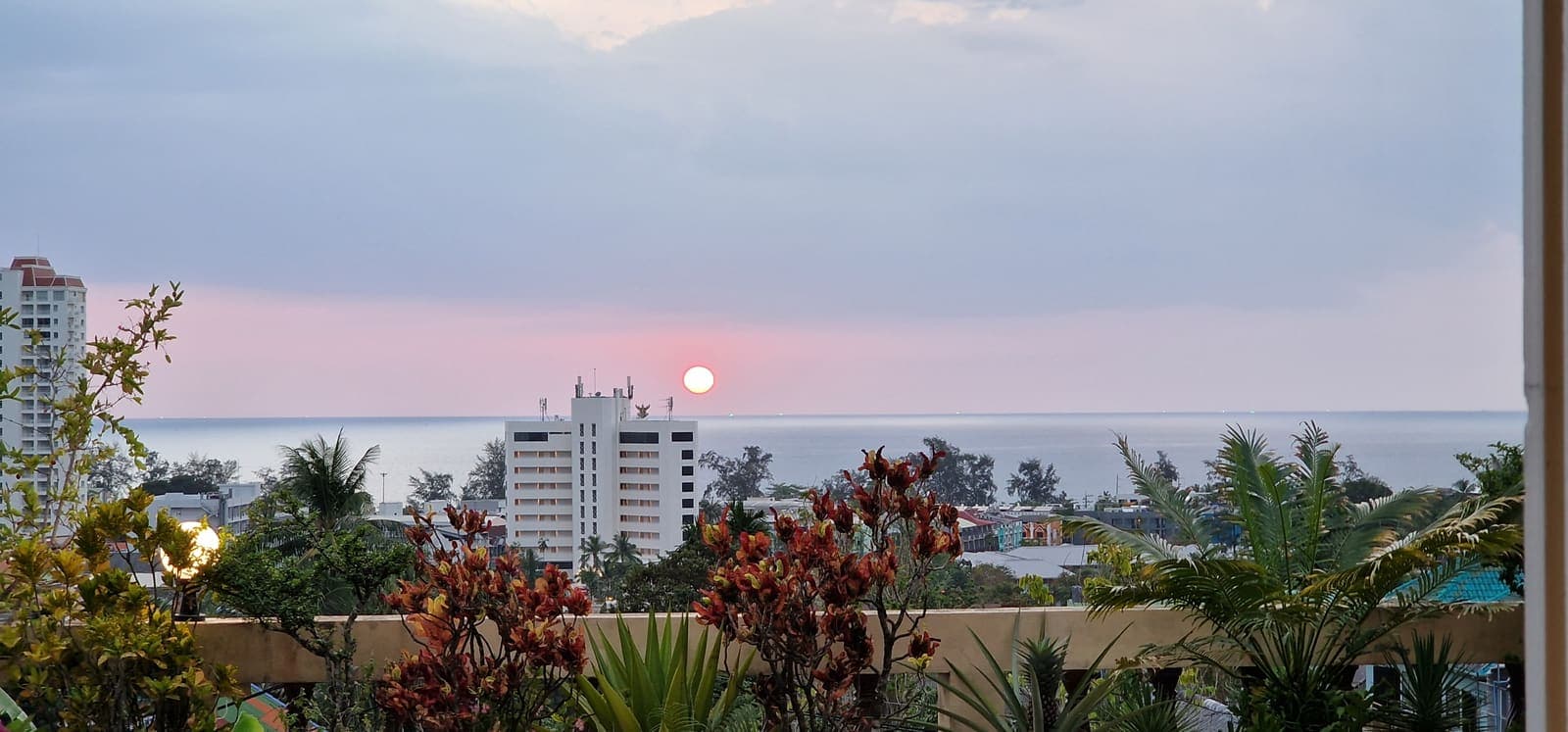 Sunset over the sea framed by balcony flowers