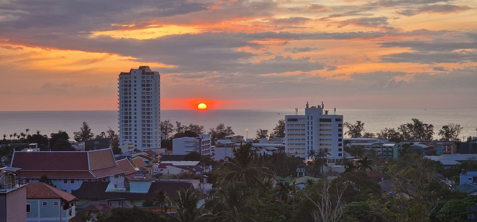 Sun setting behind a tower silhouette on the coastline