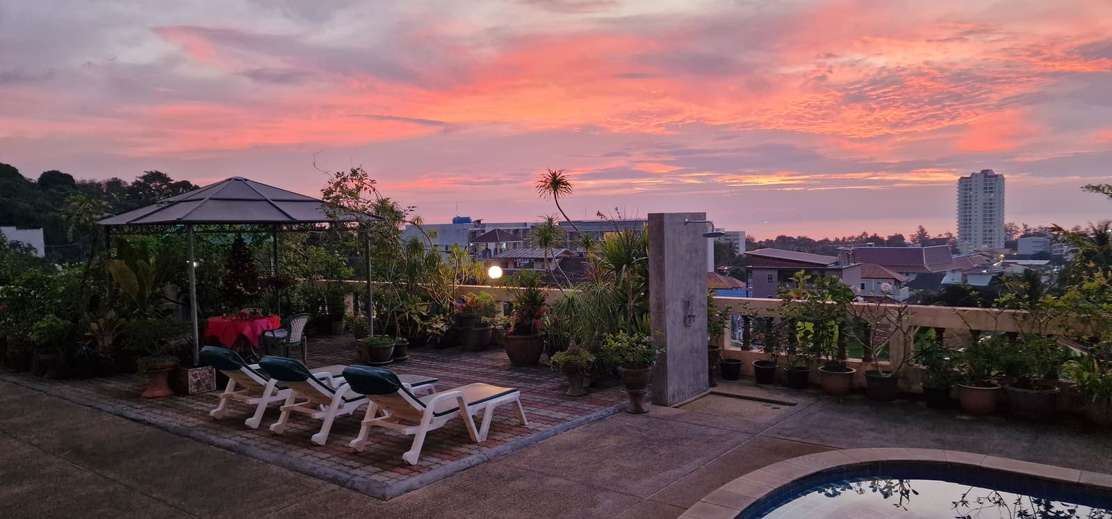 Rooftop terrace with sun loungers lit by a pink and orange sunset