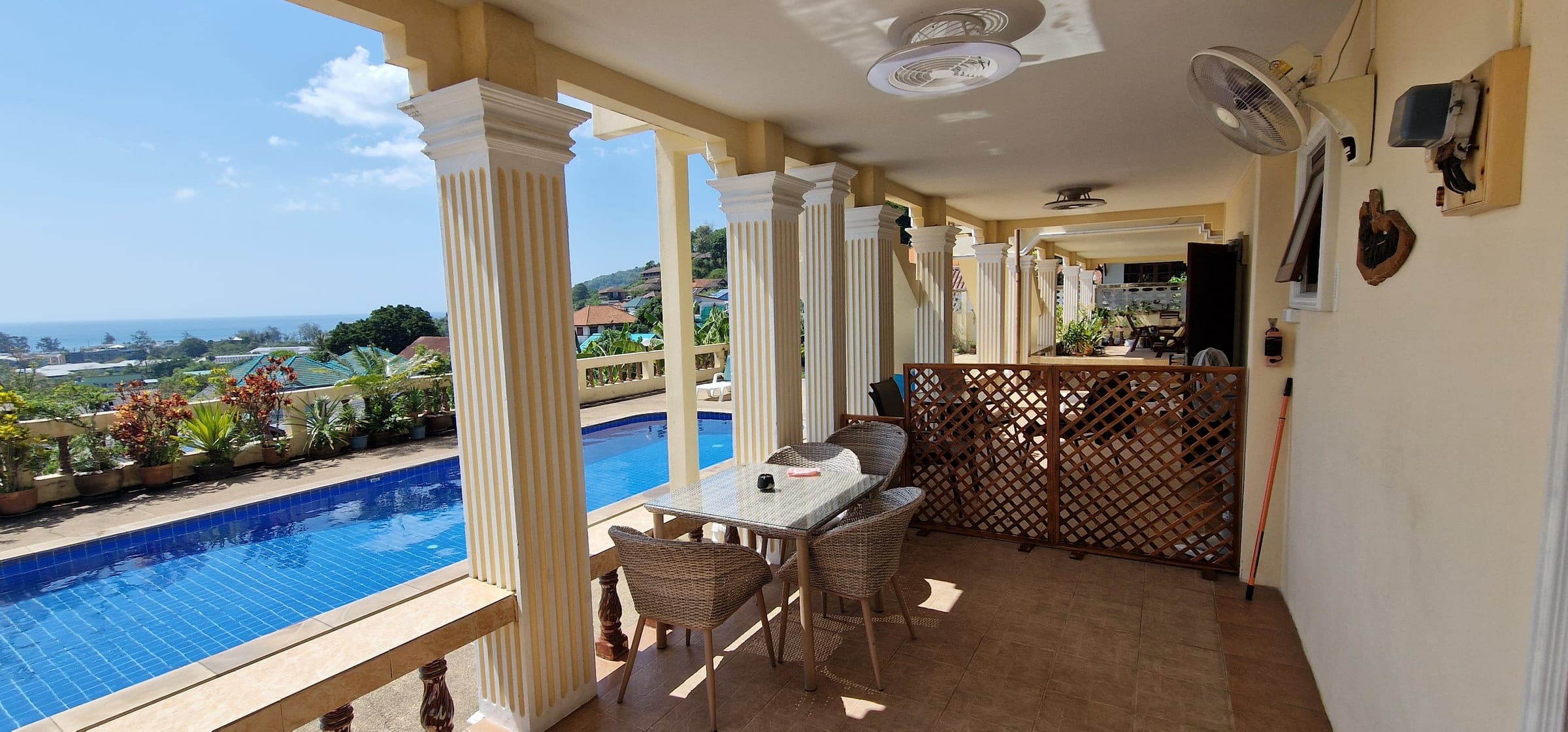 Covered terrace with classic columns overlooking the pool and the sea beyond Karon